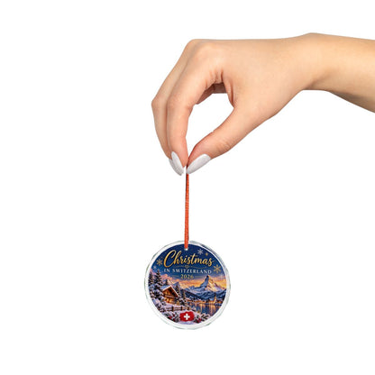 Christmas in Switzerland 2026 glass ornament held by its red ribbon, shown in hand for size